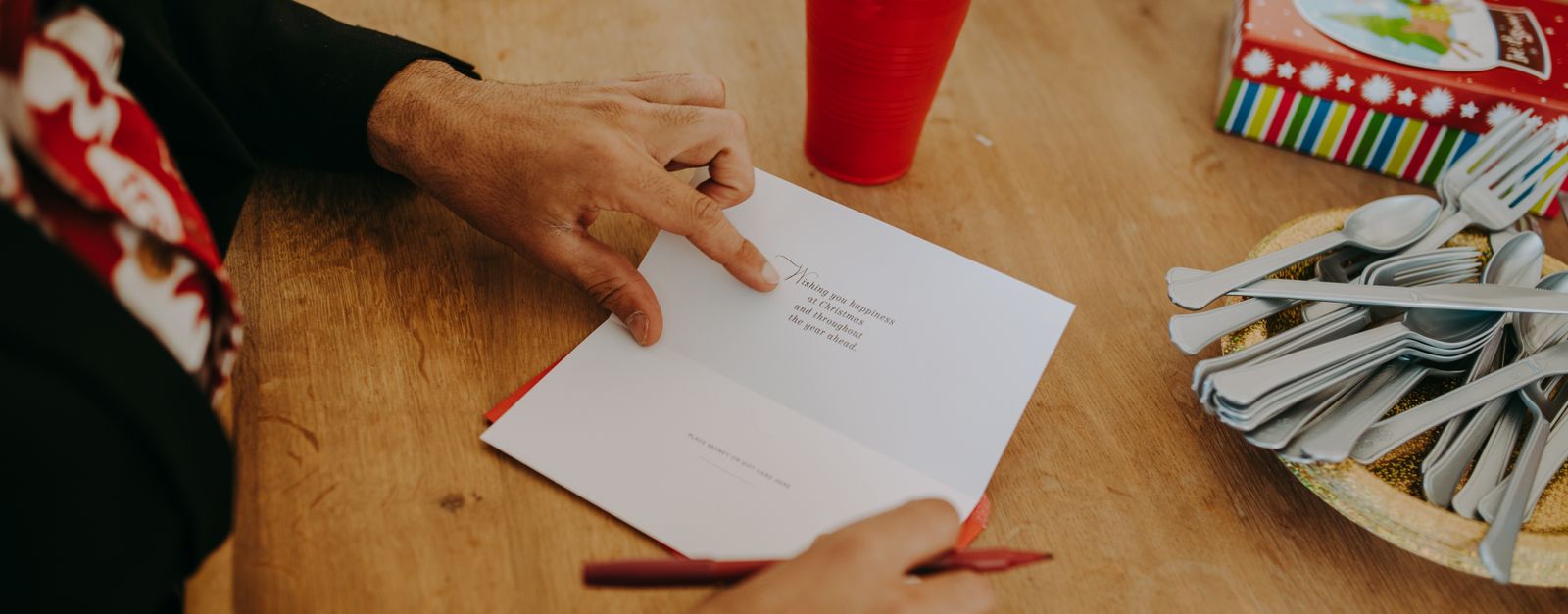 An older adult's hands with a pen at a desk, checking paperwork — the plan name on a Presbyterian member ID card is how a New Mexico member tells Dual Plus, which continues, from a plan that is ending
