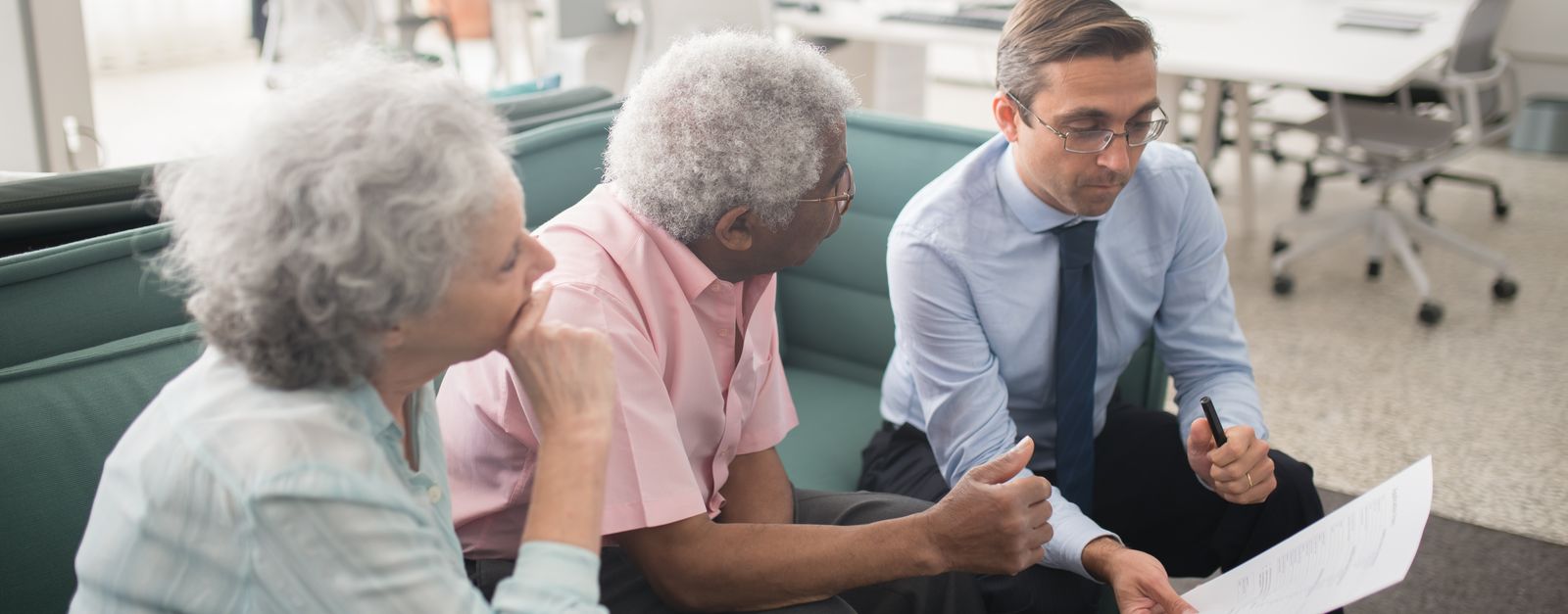 An older couple going over a printed document with an advisor — Rio Rancho members reviewing their 2027 Medicare options after the Presbyterian Medicare Advantage discontinuation, with doctors on both sides of the Sandoval and Bernalillo county line