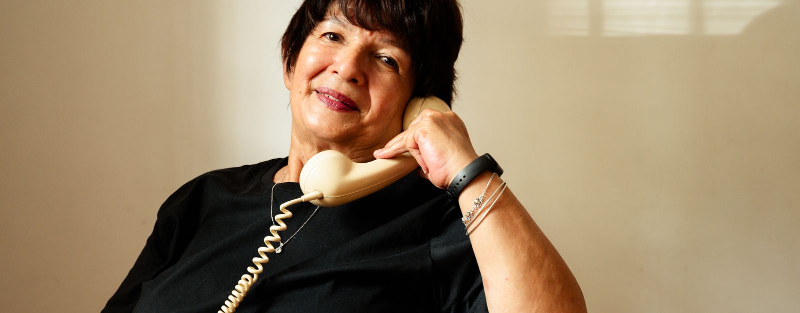 An older New Mexico woman on a phone call at home — asking whether she has to cancel her Presbyterian Medicare Advantage plan before her 2027 coverage starts