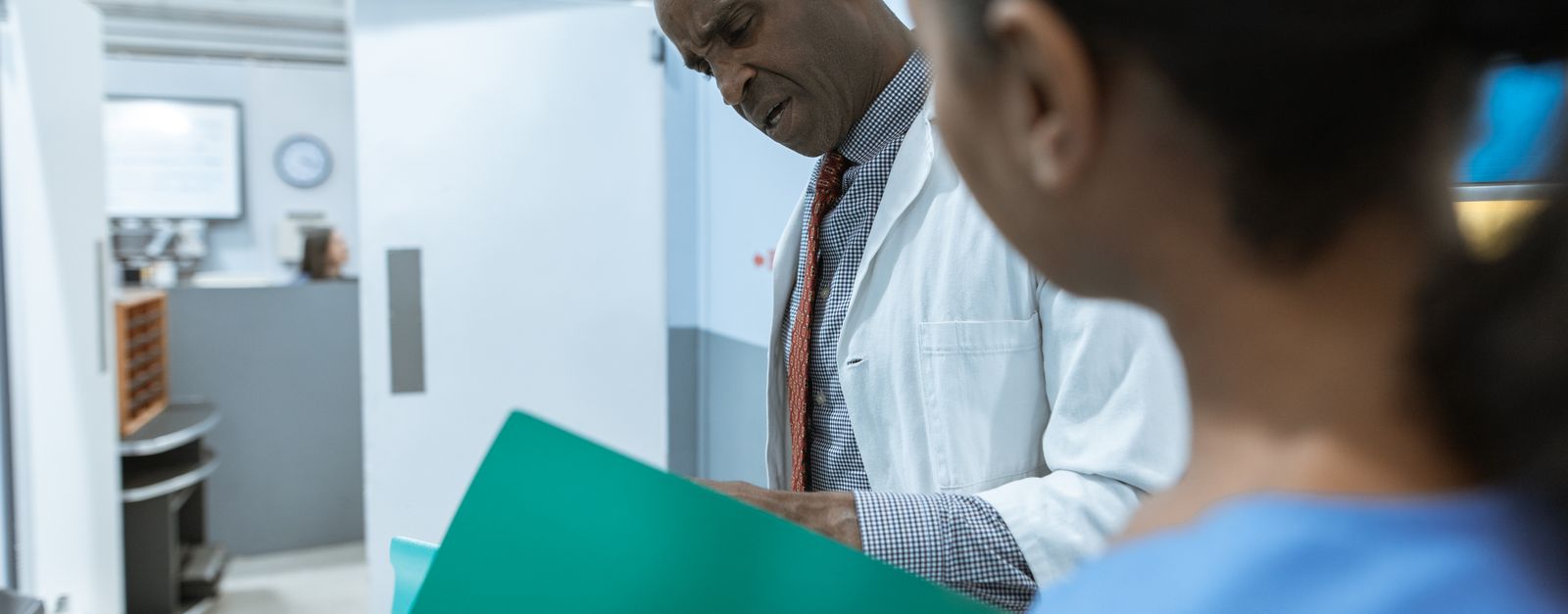 A doctor with a stethoscope around her neck sits facing the camera in a sunlit room — whether you can see a doctor like yours without a referral is one difference between a Medicare Advantage HMO and a PPO